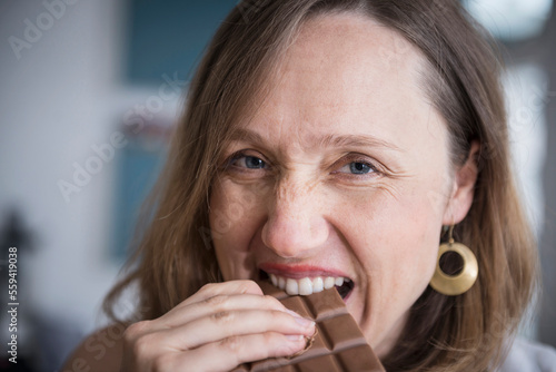 Portrait of a pregnant woman eating chocolate in the kitchen, Munich, Bavaria, Germany