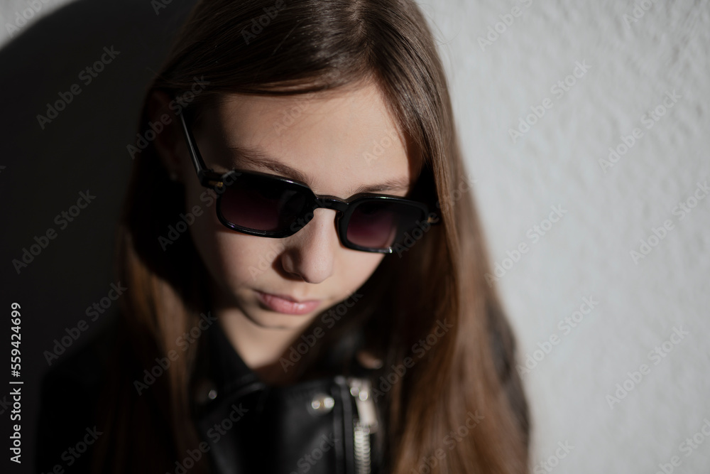 portrait of a stylish child in leather jacket with glasses on dark background with a shadows portrait of a stylish child in leather jacket with glasses on dark background with a shadows