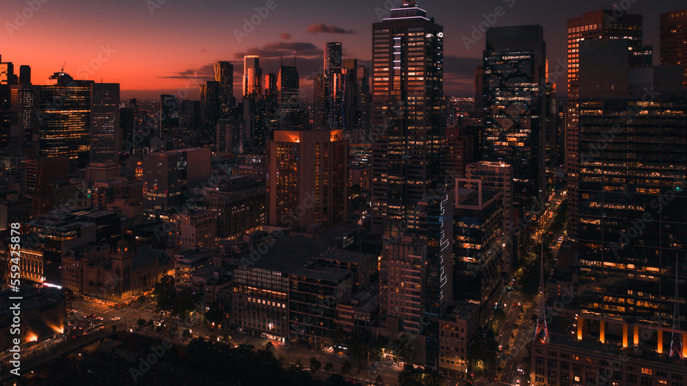Obraz premium Melbourne City Skyline Panoramic View at sunset. The sky has blue, purple and orange layered hues with orange reflections of the facades of buildings.
