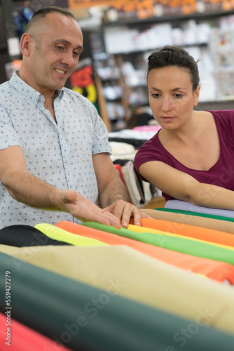 middle aged couple looking through rolls of fabric © auremar