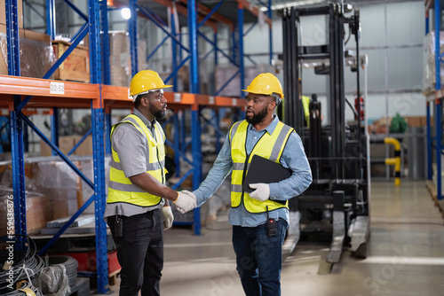 African american working in warehouse check forklift truck loading carton box smile check hand © Tongpool