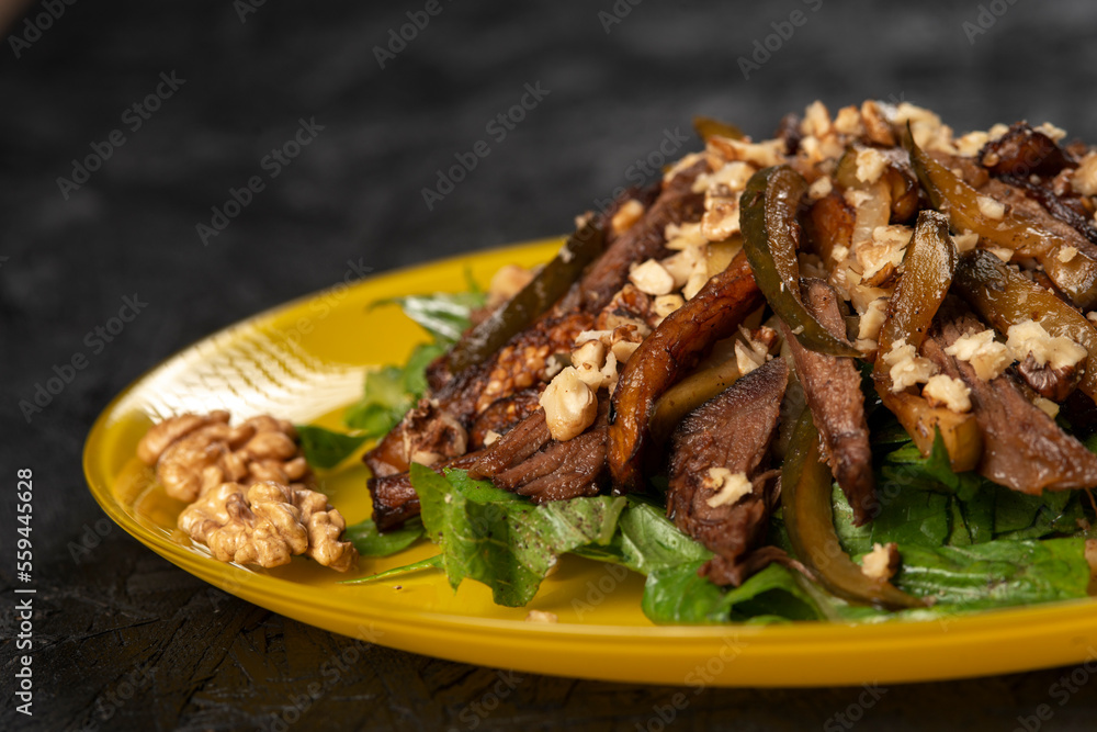 beef salad with vegetables and walnut on black background