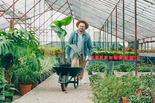 Man buys plants for new house in greenhouse garden center and puts them in cart