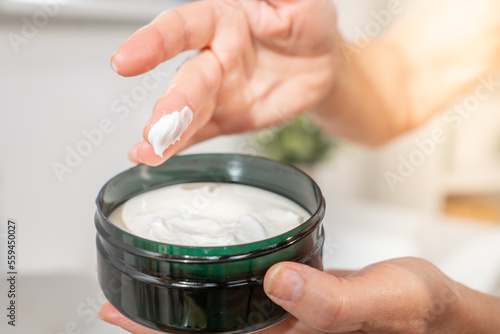 Closeup of a hand of a middle-aged woman smearing her finger with cosmetic cream for skin care and beauty. anti-aging anti-wrinkle concept