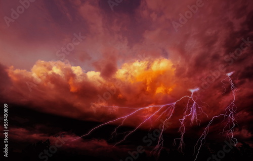 lightning on fiery clouds in the sky, colorful dramatic sky with clouds and steaming cumulonimbus clouds reflect the golden light of the morning sun.