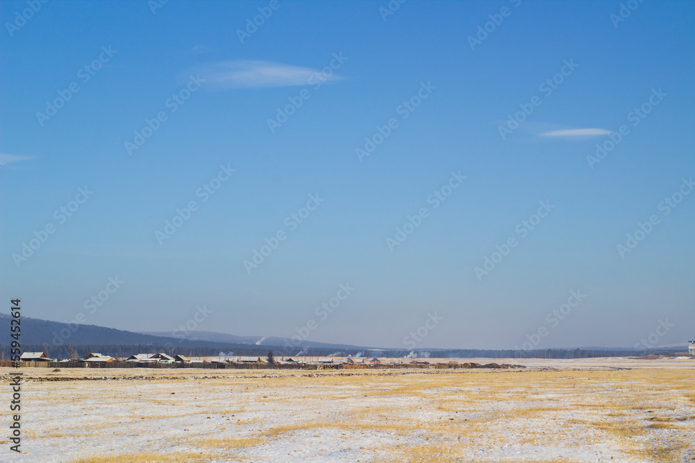 Scenic view of small village and snowcapped mountains in winter Scenic view of small village and snowcapped mountains in winter