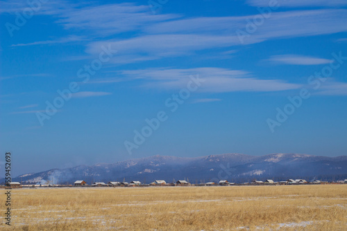 Scenic view of small village and snowcapped mountains in winter