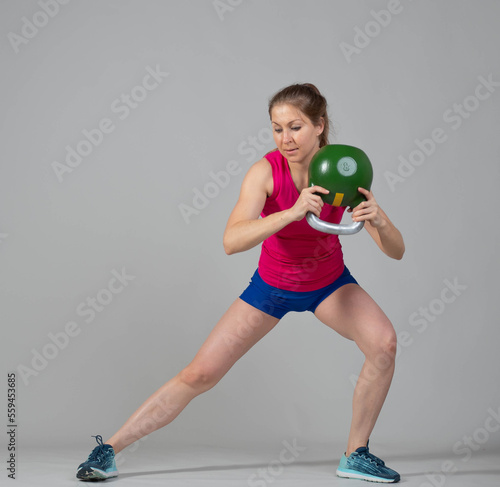 Training with kettlebells, a young athlete performs exercises with kettlebells, lunges with weights