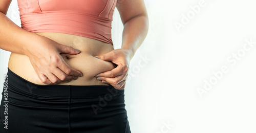 Body care concept : Woman's hand pinching her excess belly fat, Fat unhealthy woman cellulite  body isolated on white background photo
