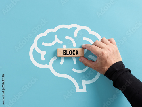 Mental block concept. To remove or generate mental blocks of the human mind. Hand puts a wooden block with the word block on a human brain symbol.