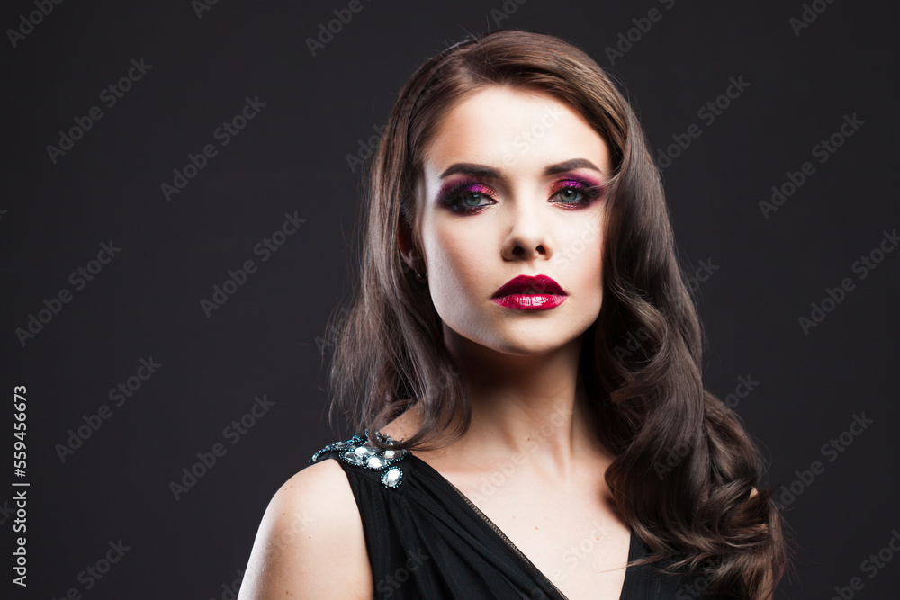 Portrait of a young luxurious woman in a low key. Bright makeup with scarlet lipstick, hairstyle with curls, portrait on a black background Portrait of a young luxurious woman in a low key. Bright makeup with scarlet lipstick, hairstyle with curls, portrait on a black background