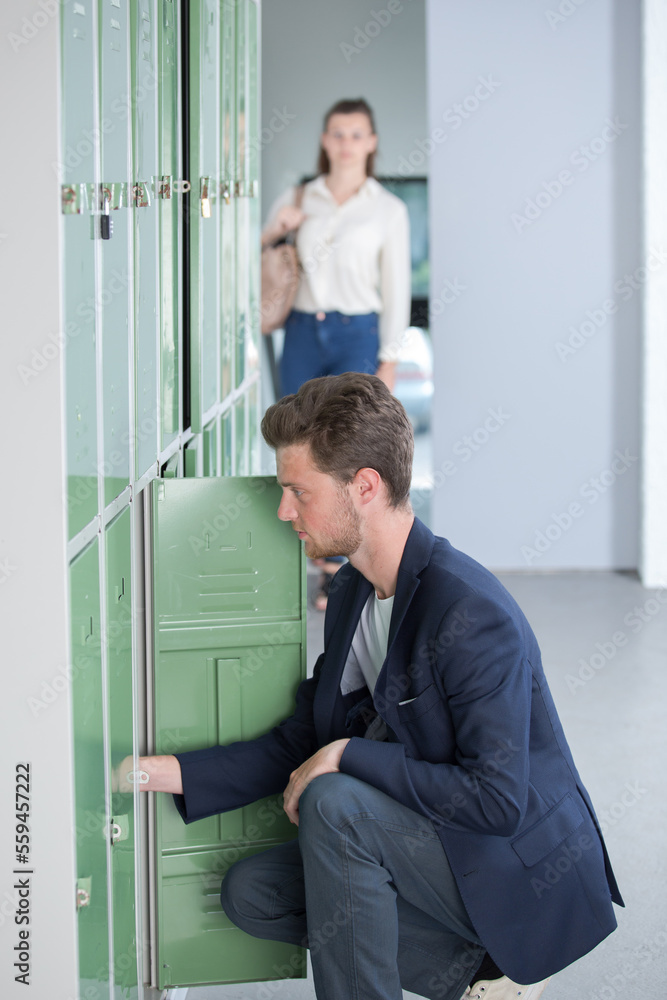 male student opening a locker at college