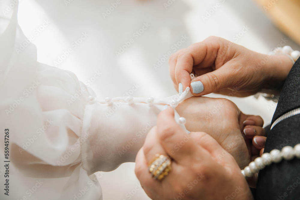 mom fastens the bride's sleeves close-up