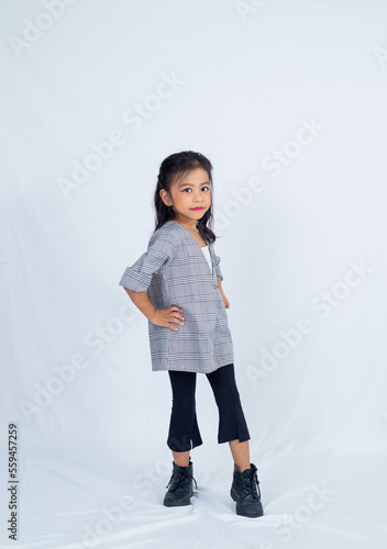 Pretty little girl in a studio white background. Asian kid model posing in style indoor. 