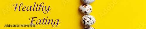 fresh Spotted Quail eggs in a row.Organic eggs on yellow table. Healthy food concept. web banner.Top view, copy space. Selective focus. text healthy eating