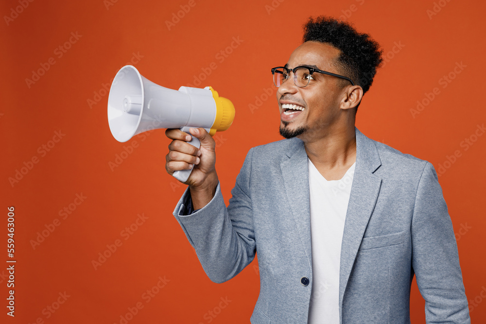 Young fun employee business man corporate lawyer in formal grey suit shirt glasses work in office scream in megaphone announces discounts sale Hurry up isolated on plain red orange background studio Young fun employee business man corporate lawyer in formal grey suit shirt glasses work in office scream in megaphone announces discounts sale Hurry up isolated on plain red orange background studio