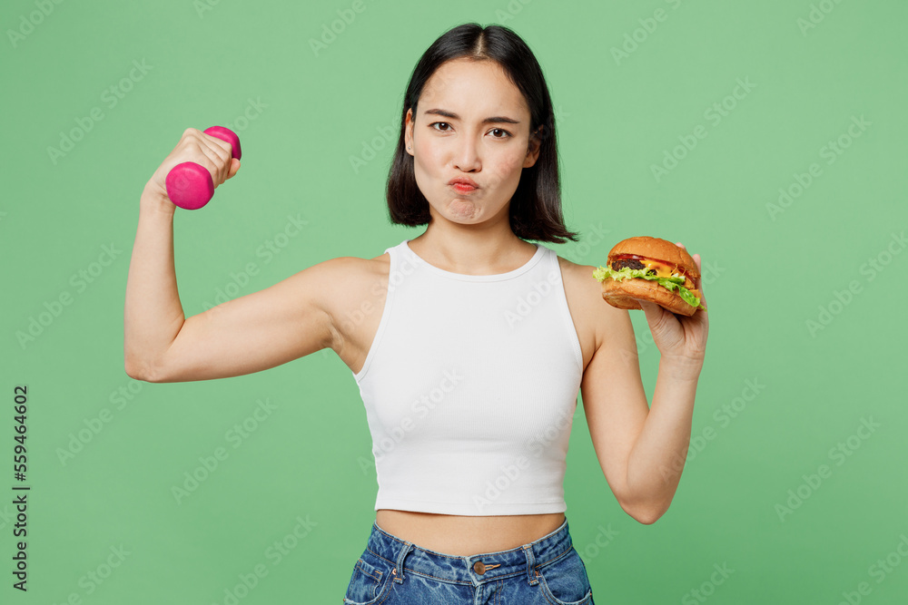 Φωτογραφία Young woman wear white clothes hold eat burger dumbbel burns calories do sport w