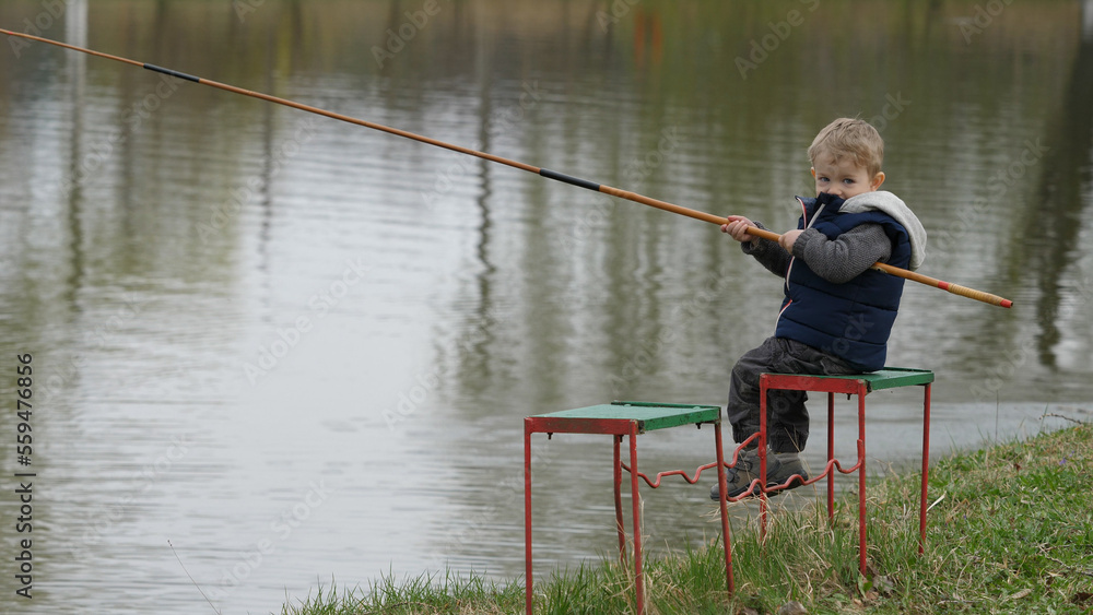 Small child learns to fish, sweet boy with blond hair look at camera Small child learns to fish, sweet boy with blond hair look at camera