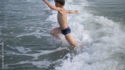 Child jump over sea waves, summer holiday fun