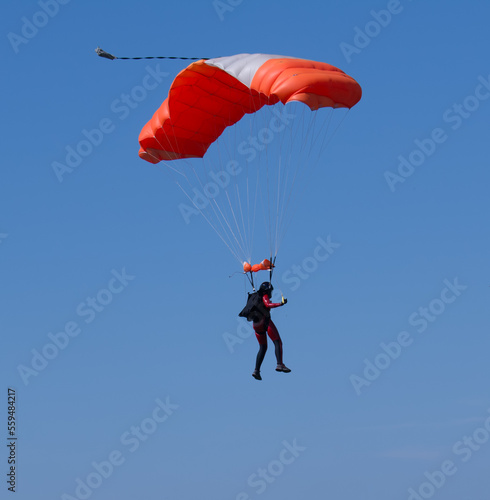 Skydiver with a colorful parachute on a blue sky background.