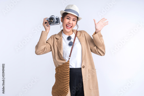ready to travel ,young teen asian smiling cheerful female woman casual cloth hand hold camera standing with luggage case bag prepare to new abroad journey travel studio shot on white background