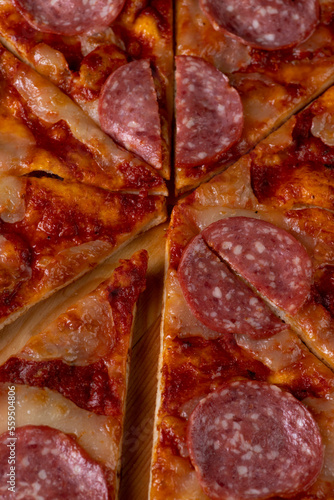 Pizza on a plate on a wooden background, cut into pieces