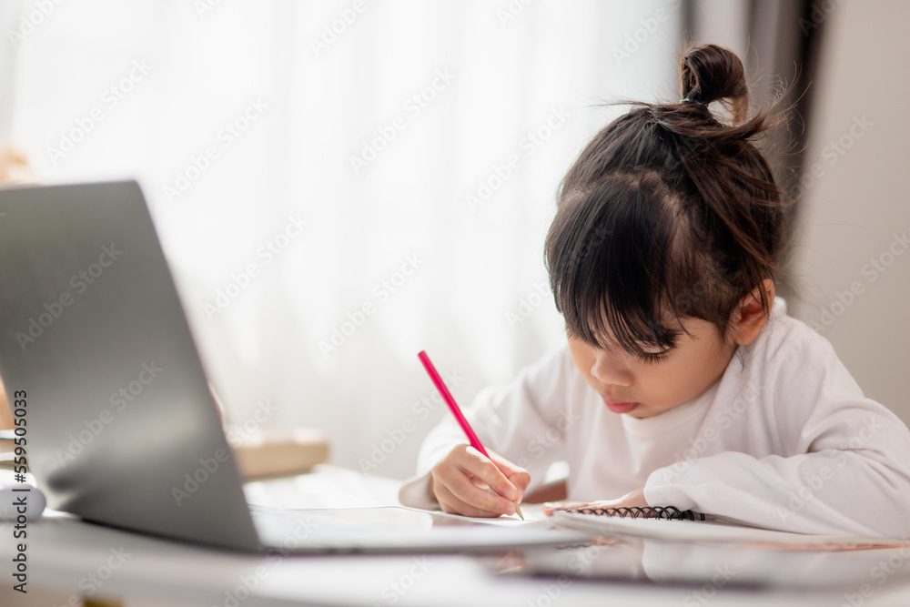 Asian schoolgirl doing her homework with laptop at home. Children use gadgets to study. Education and distance learning for kids. Homeschooling during quarantine. Stay at home Asian schoolgirl doing her homework with laptop at home. Children use gadgets to study. Education and distance learning for kids. Homeschooling during quarantine. Stay at home