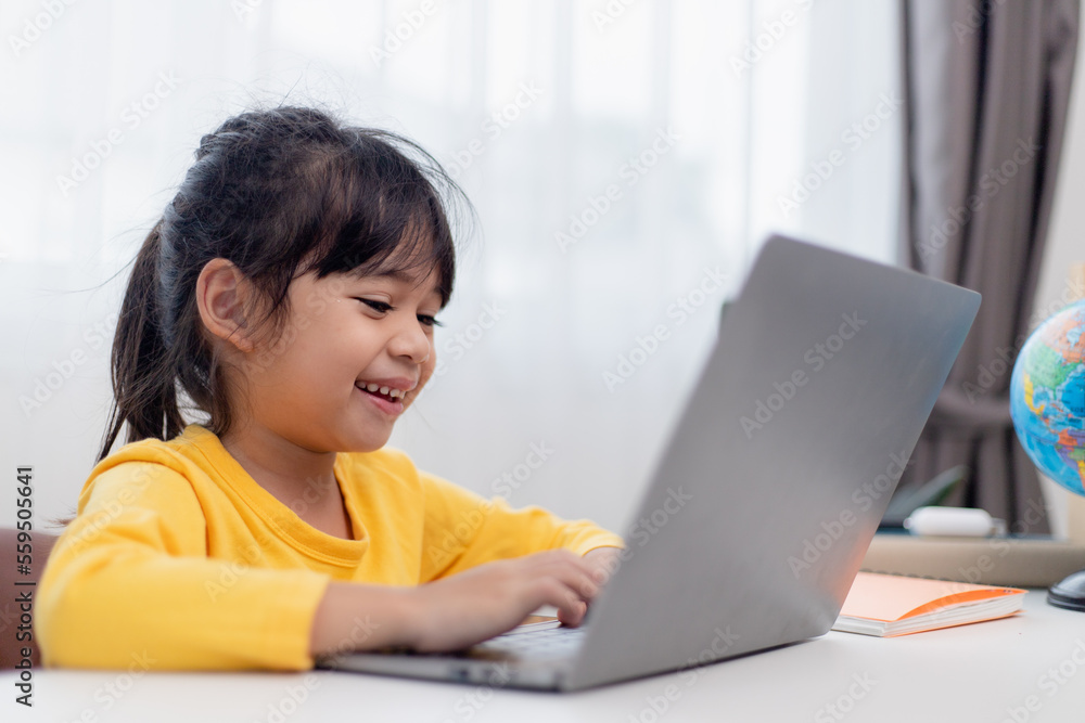 First day at school. Asian little girl using a laptop computer, studying through online e-learning system. First day at school. Asian little girl using a laptop computer, studying through online e-learning system.