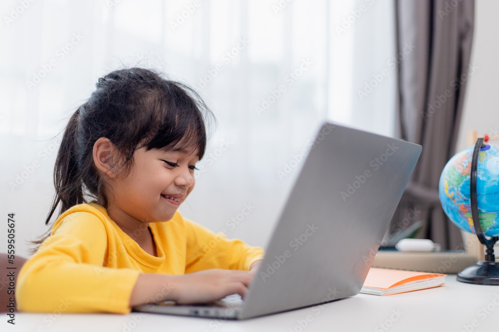 First day at school. Asian little girl using a laptop computer, studying through online e-learning system.