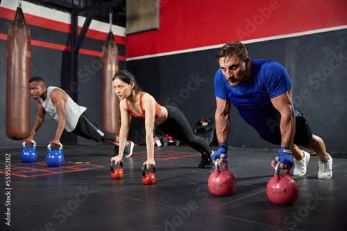 sportsman doing push up on two kettlebells in the gym