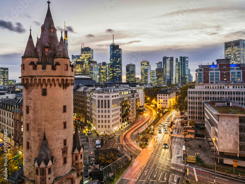 Eschenheim Tower, old and new Frankfurt city buildings with light rail after sunset, Germany