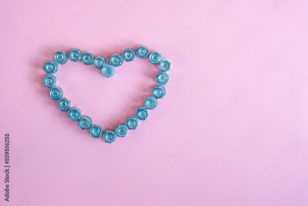 Bright pink background with a heart of bolts and nuts. The concept of the Valentine's Day holiday. Beautiful background and free space for text.