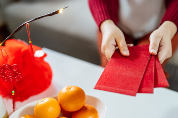 Asian Woman giving red envelope for Lunar New Year celebrations. Hand hold red packet