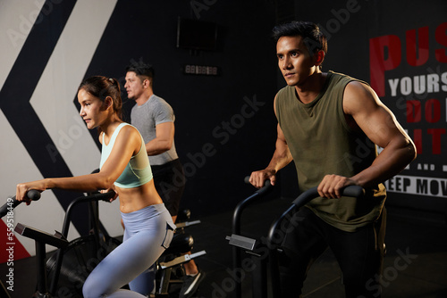 young athletic man cycling exercise bikes at the gym