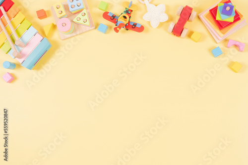 Baby kids toys frame background. Wooden educational, sensory, musical, building, sorting and stacking toys for children on yellow background. Montessori, susitainable toys. Top view, flat lay