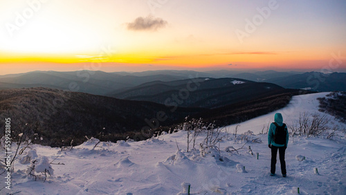 backpacker girl walks along the top of snowy mountains bieszczady at sunset, winter sunset seen from the top of the mountain wielka rawka
