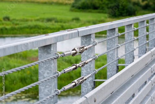 Turnbuckles connecting the safety ropes at the railing on the bridge. Summer. © W Korczewski