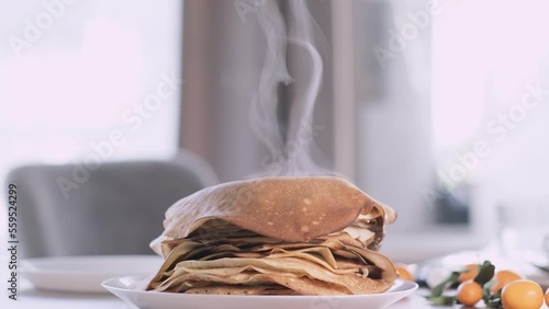 Sweet french and russian homemade thin pancakes crepes, Stack of fresh baked crepes with raised steam on morning table breakfast. photo