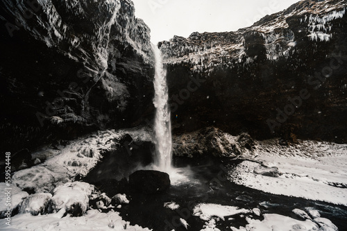 Kvernufoss waterfall, Iceland. Icelandic winter landscape. High waterfall and rocks. Snow and ice photo