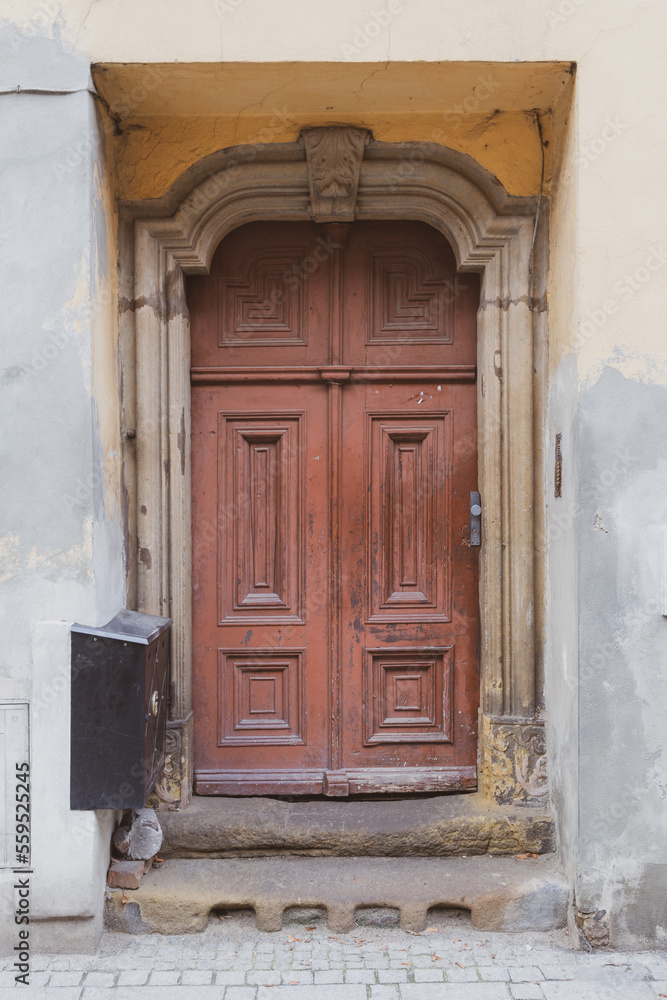 An old wooden brown-painted tenement door. 
