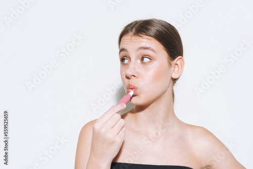 Beauty portrait of funny young girl with fresh skin  teenager doing lips makeup on white background isolated