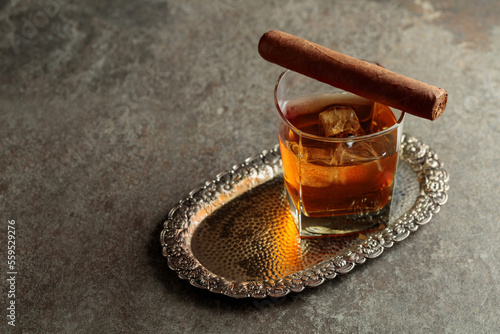 Whiskey with ice and cigar on an old stone table. © Igor Normann