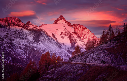 Incredible scenery of European Alps in during sunset. Grossglockner peak glowing in sunlight with perfect colorful sky. Grossglockner High Alpine is a most popular place of travel.
