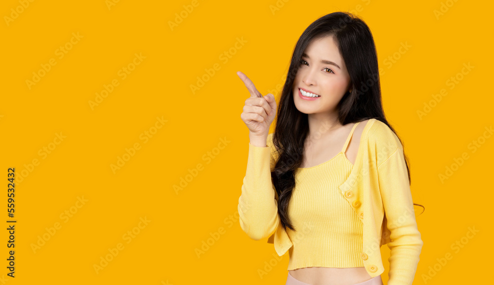Beautiful young Asian woman pointing up to copy space and looking at camera with smile face and happy Pretty girl act like a satisfied product, use for advertising with isolated on yellow background Beautiful young Asian woman pointing up to copy space and looking at camera with smile face and happy Pretty girl act like a satisfied product, use for advertising with isolated on yellow background