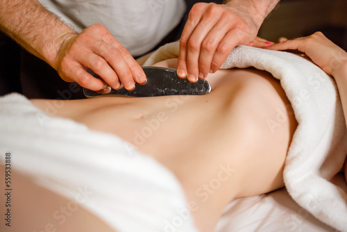 Male chiropractor is treating woman abdominal muscles by IASTM technology photo