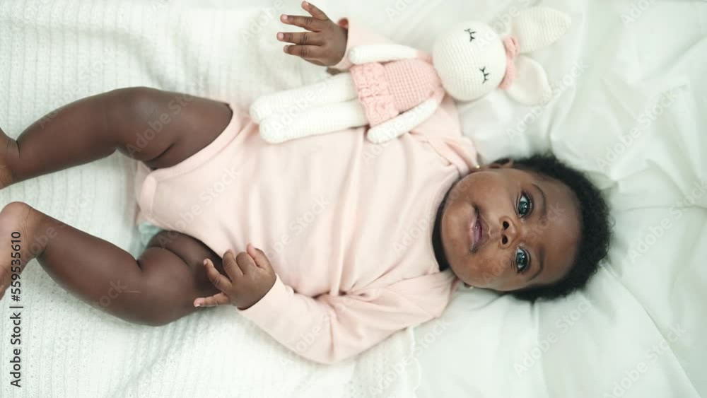 African american baby lying on bed with relaxed expression at bedroom