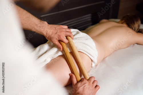 Female buttocks massage with bamboo sticks at the spa
