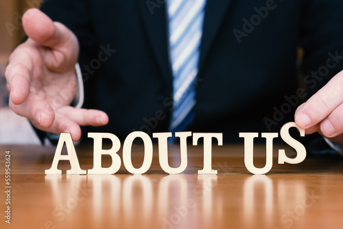 ABOUT US  in letter tiles on desk top with business person placing the final S. 