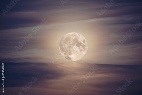 brightly lit full moon among the clouds in the night sky