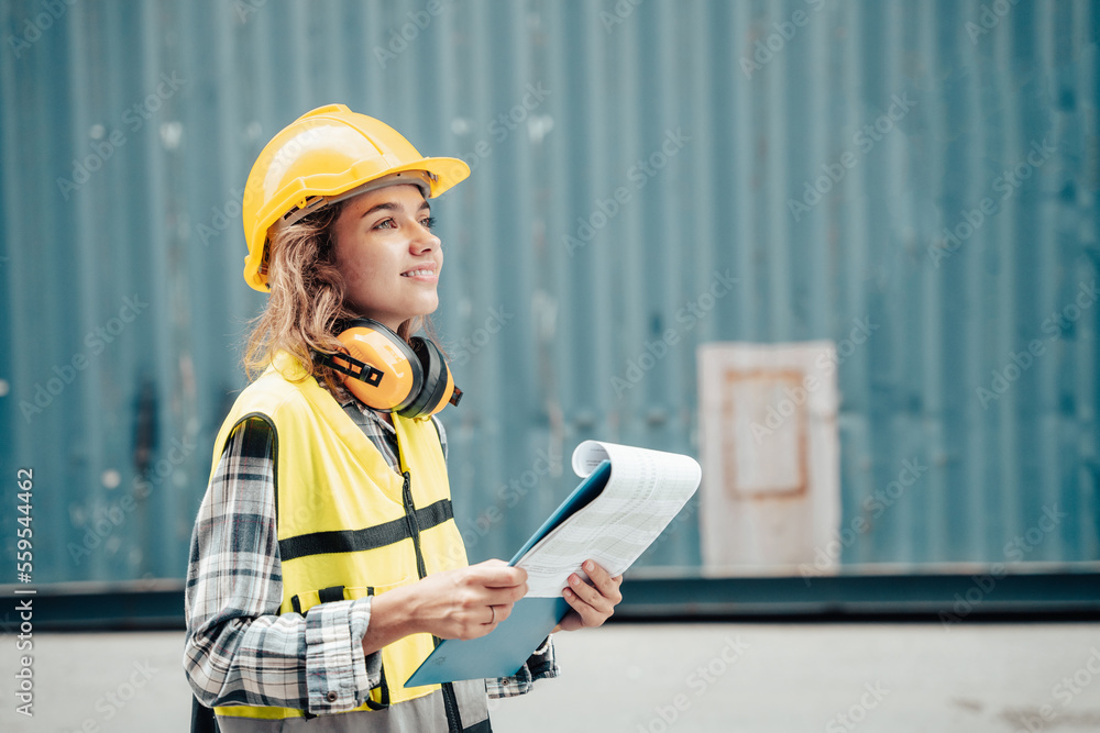 Female foreman wearing a helmet inspects a container.